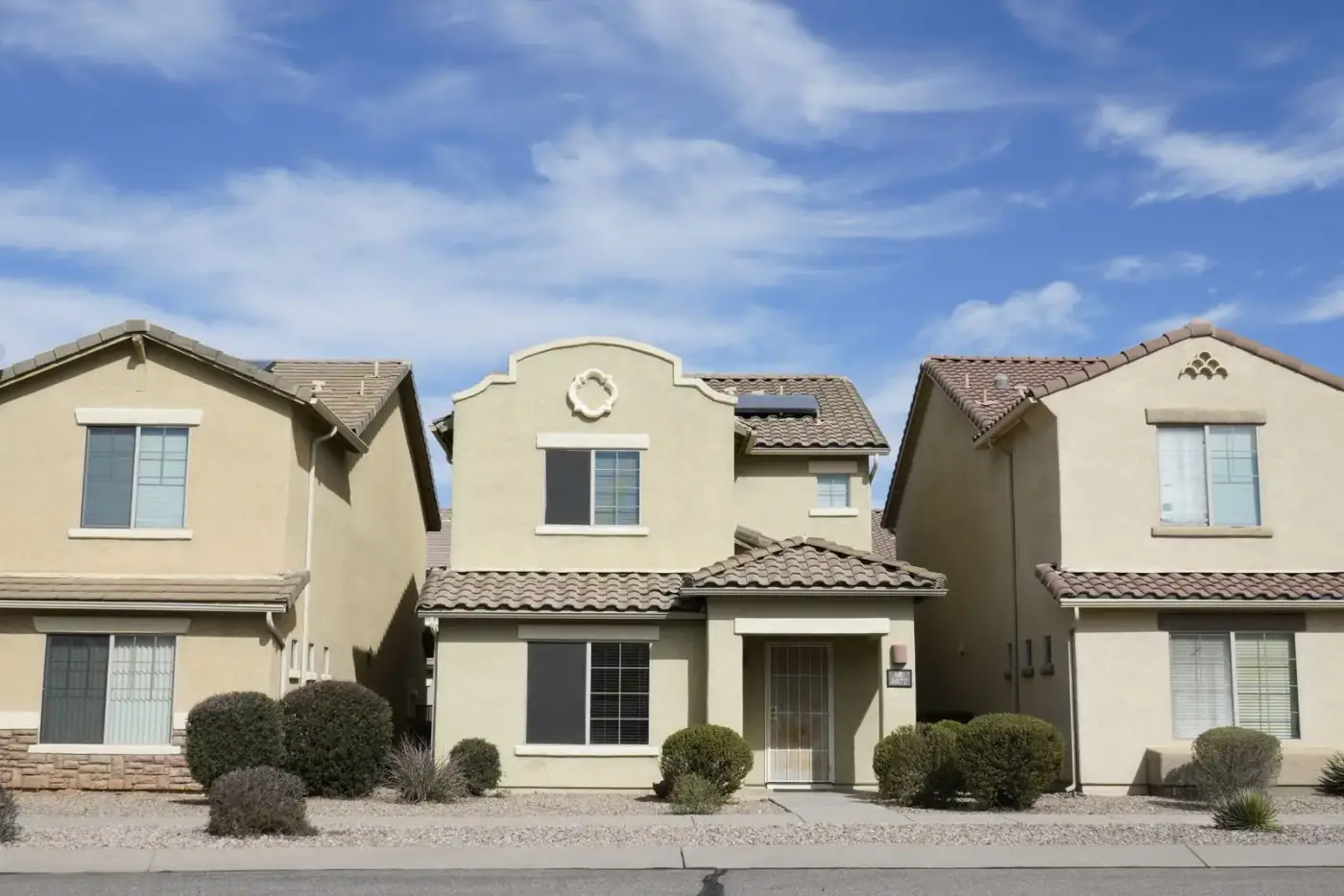 Two-story stucco homes with tile roofs in a desert suburb