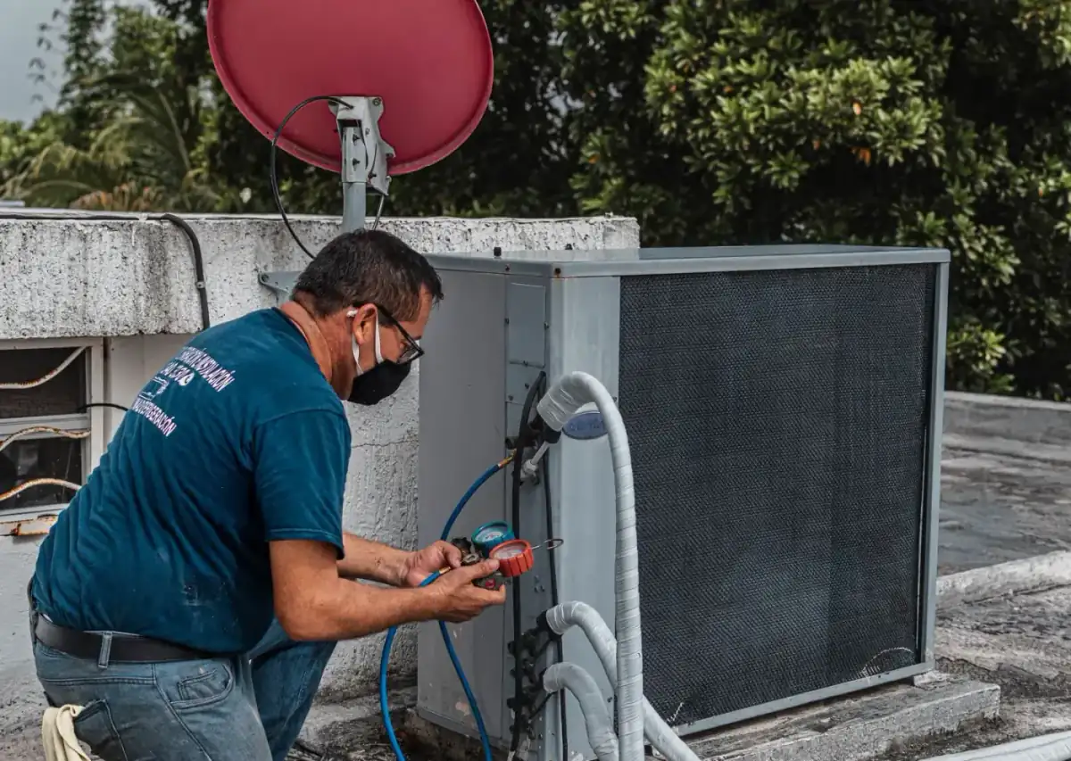 HVAC technician testing a rooftop condenser with gauges